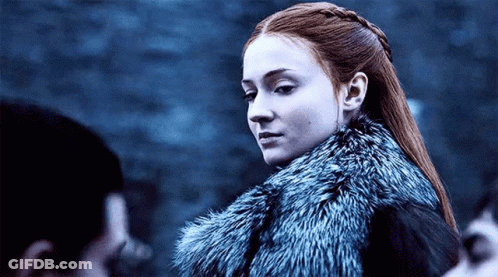 A Woman With Red Hair Is Wearing A Fur Coat And Looking At The Camera . GIF