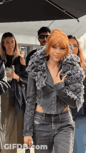 A Woman With Red Hair Is Wearing A Grey Jacket GIF
