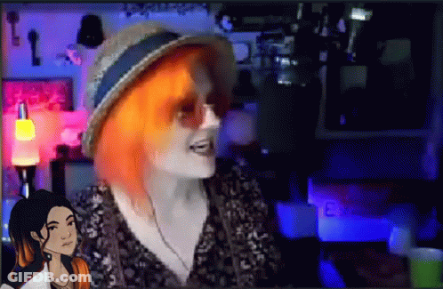 A Woman With Red Hair Is Wearing A Hat And Sunglasses While Talking To Another Woman . GIF