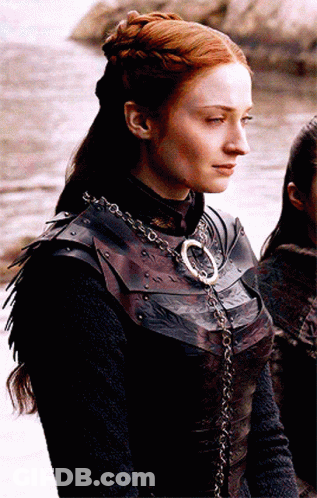 A Woman With Red Hair Is Wearing A Leather Armor And A Necklace With The Letter O On It GIF