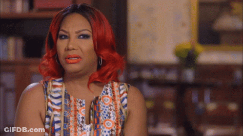 A Woman With Red Hair Is Wearing A Multicolored Top GIF