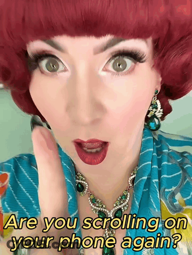 A Woman With Red Hair Is Wearing A Necklace And Earrings And Says Are You Scrolling On Your Phone Again GIF