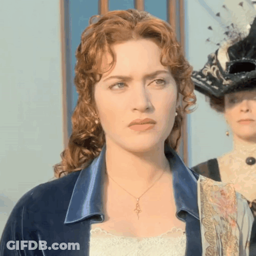 A Woman With Red Hair Is Wearing A Necklace That Has A Key On It GIF