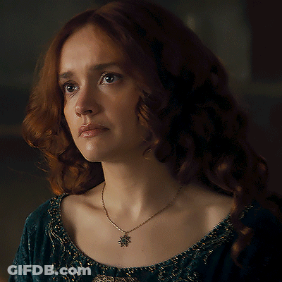 A Woman With Red Hair Is Wearing A Necklace With A Leaf Pendant GIF