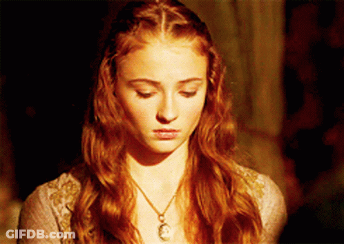 A Woman With Red Hair Is Wearing A Necklace With A Pendant On It GIF