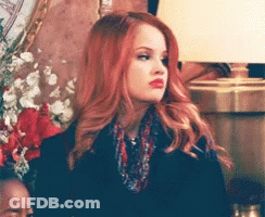 A Woman With Red Hair Is Wearing A Scarf And A Black Jacket GIF