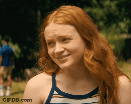 A Woman With Red Hair Is Wearing A Striped Tank Top And Smiling GIF