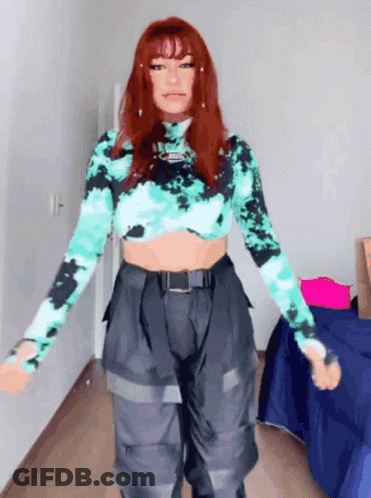 A Woman With Red Hair Is Wearing A Tie Dye Crop Top And Cargo Pants GIF