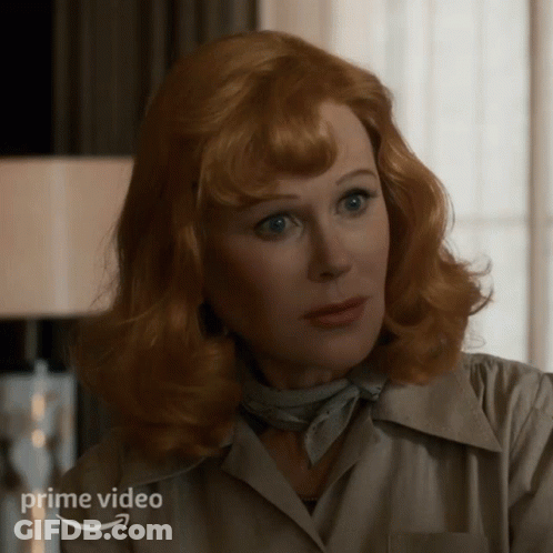 A Woman With Red Hair Is Wearing A White Shirt And A Scarf And The Word Prime Video Is On The Bottom GIF