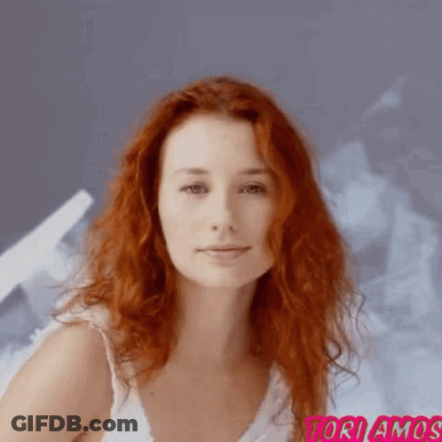 A Woman With Red Hair Is Wearing A White Tank Top And The Word Toriamos Is On The Bottom Right GIF