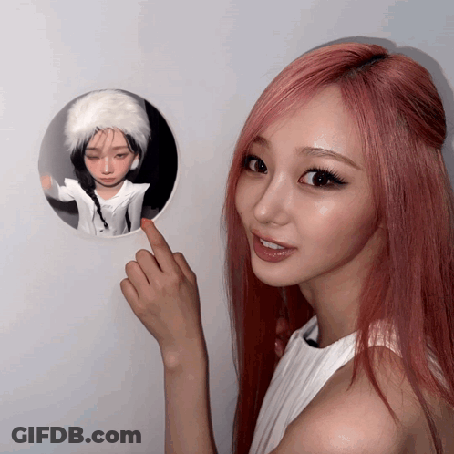 A Woman With Red Hair Points To A Picture Of A Girl GIF