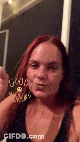 A Woman With Red Hair Says Good Morning With A Smiley Face On Her Face GIF