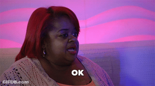 A Woman With Red Hair Says Ok In A Purple Background GIF