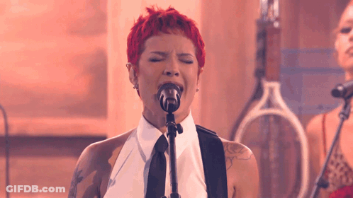 A Woman With Red Hair Singing Into A Microphone With Her Eyes Closed GIF