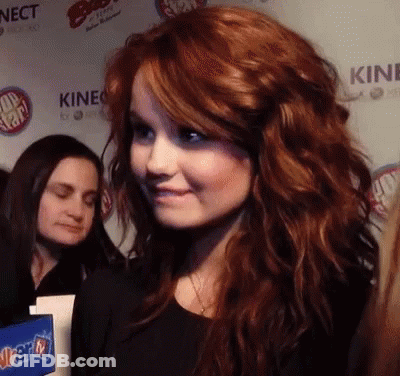 A Woman With Red Hair Stands In Front Of A Wall That Says Kinect On It GIF