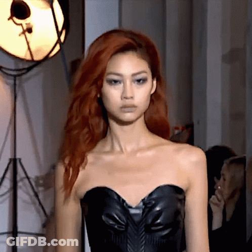 A Woman With Red Hair Wearing A Black Strapless Top GIF