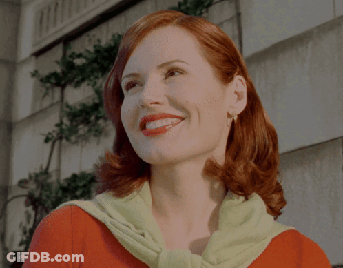 A Woman With Red Hair Wearing A Green Sweater Smiles GIF