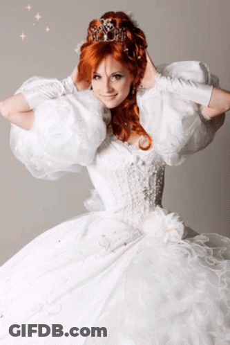 A Woman With Red Hair Wearing A White Dress And A Tiara GIF