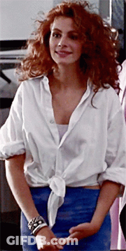A Woman With Red Hair Wearing A White Shirt And A Blue Skirt GIF