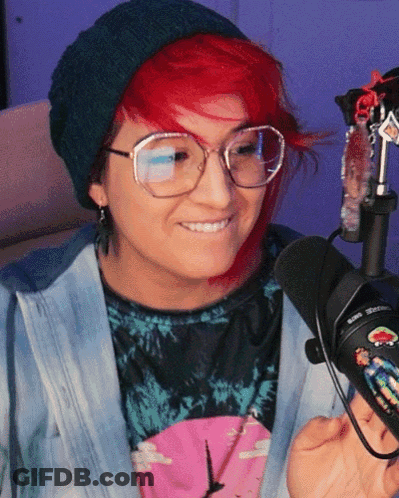 A Woman With Red Hair Wearing Glasses And A Beanie GIF