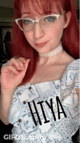 A Woman With Red Hair Wearing Glasses And A Choker Has The Word Hiya Written On Her Top GIF