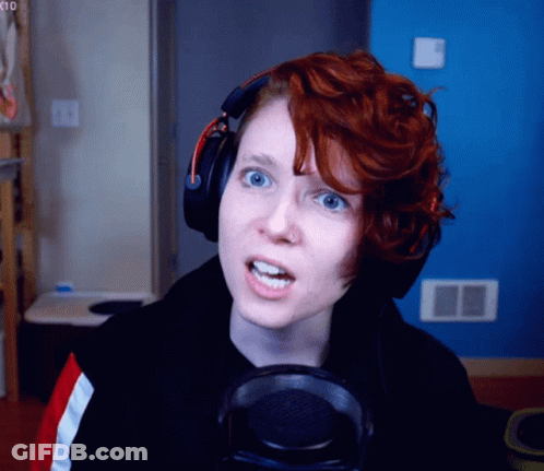 A Woman With Red Hair Wearing Headphones Looks At The Camera GIF