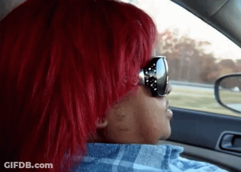 A Woman With Red Hair Wearing Sunglasses And A Plaid Shirt GIF