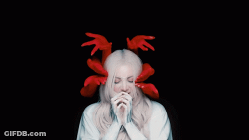 A Woman With Red Hands On Her Head And A White Robe GIF