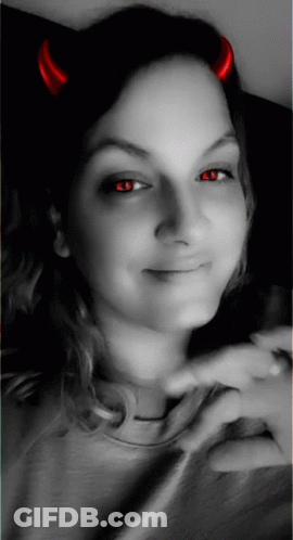 A Woman With Red Horns On Her Head Is Smiling GIF