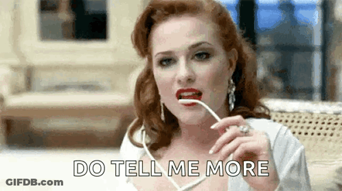 A Woman With Red Lips Is Holding A Pair Of Glasses In Her Mouth And Saying `` Do Tell Me More '' . GIF