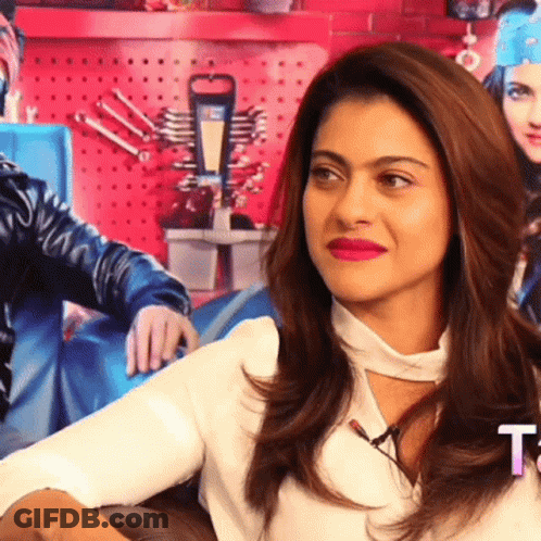 A Woman With Red Lipstick Is Sitting In Front Of A Sign That Says T. GIF