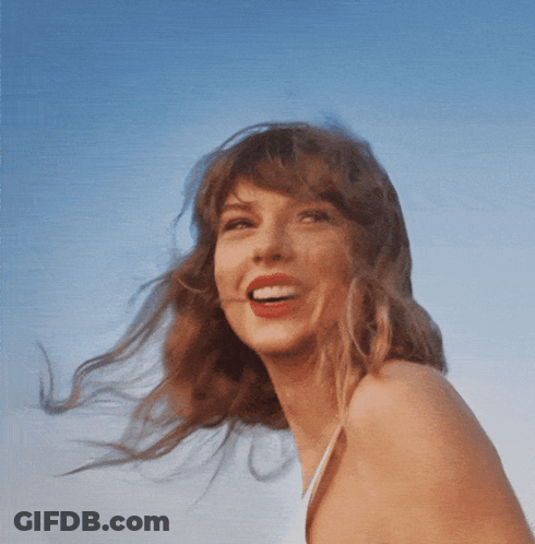 A Woman With Red Lipstick Is Smiling And Her Hair Is Blowing In The Wind GIF