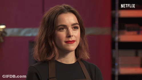 A Woman With Red Lipstick Is Standing In Front Of A Sign That Says Netflix On It GIF