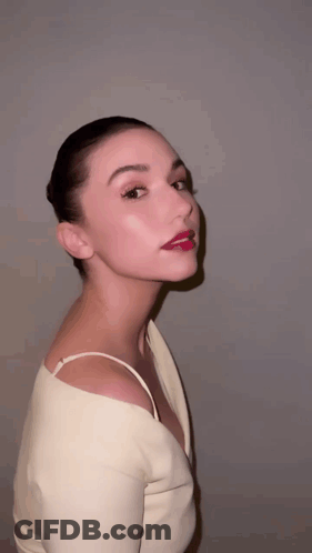 A Woman With Red Lipstick On Her Lips Is Wearing A Very Revealing Top GIF