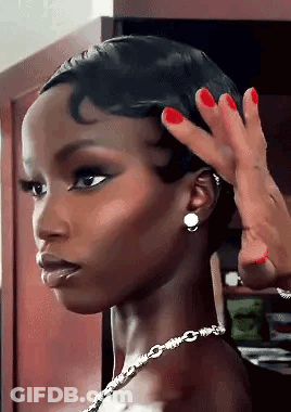 A Woman With Red Nails And A Necklace Is Getting Her Hair Done . GIF