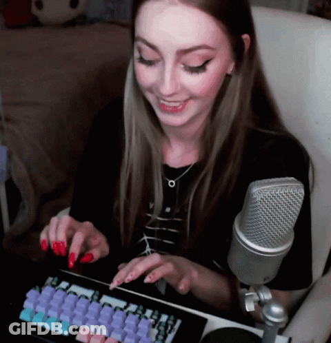 A Woman With Red Nails Is Typing On A Keyboard In Front Of A Silver Microphone GIF