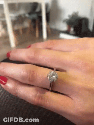 A Woman With Red Nails Is Wearing A Diamond Ring On Her Left Hand GIF