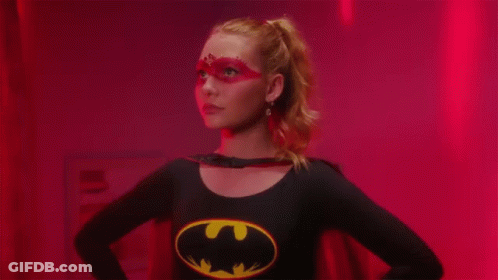 A Woman With Red Paint On Her Face And A Batman Shirt On GIF
