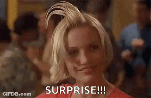 A Woman With Short Blonde Hair Is Smiling And Holding Her Hair Up In The Air . GIF