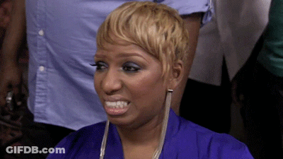 A Woman With Short Blonde Hair Is Wearing A Blue Shirt And Earrings . GIF