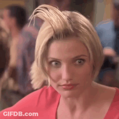 A Woman With Short Blonde Hair Is Wearing A Red Shirt And Looking At The Camera . GIF