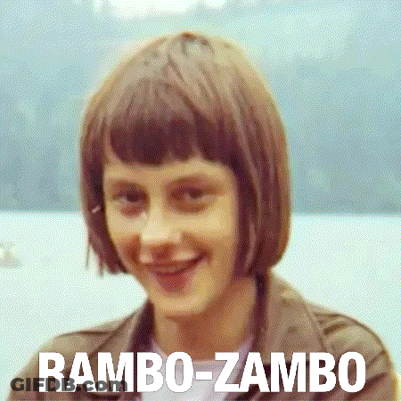 A Woman With Short Brown Hair Is Smiling With The Words Rambo-Zambo Behind Her GIF