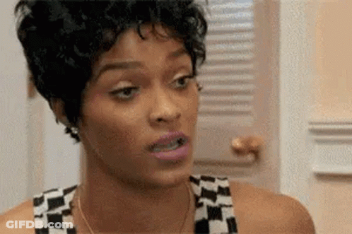 A Woman With Short Curly Hair Is Making A Funny Face In Front Of A Window . GIF