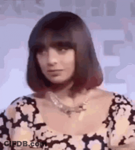 A Woman With Short Hair And A Necklace Is Wearing A Black And White Dress . GIF