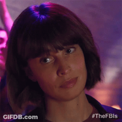 A Woman With Short Hair And Bangs Is Looking At The Camera In A Club . GIF