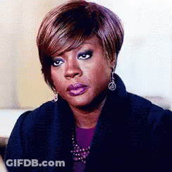 A Woman With Short Hair And Earrings Is Sitting On A Couch . GIF