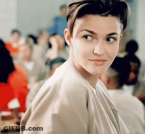 A Woman With Short Hair Is Looking At The Camera In Front Of A Crowd . GIF