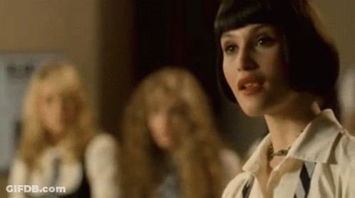 A Woman With Short Hair Is Standing In Front Of A Group Of Women . GIF
