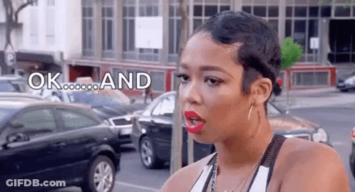 A Woman With Short Hair Is Standing On A Street With Cars Parked In Front Of Her . GIF