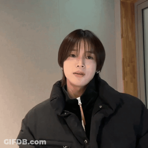 A Woman With Short Hair Is Wearing A Black Jacket And Earrings GIF